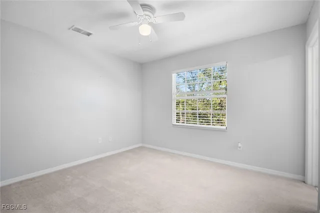 an empty room with a window and a fan