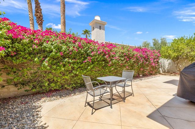a patio with table and chairs and potted plants
