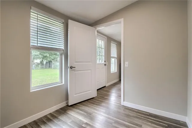 an empty room with wooden floor and windows