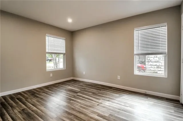 an empty room with wooden floor & windows