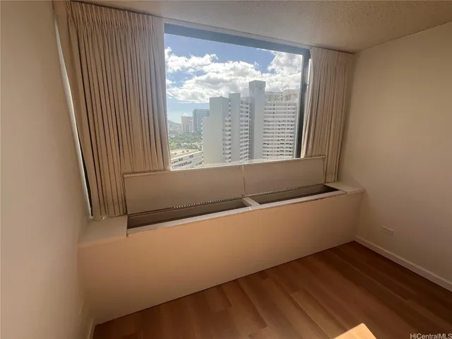 a view of an empty room with wooden floor and a window