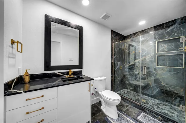 a bathroom with a granite countertop sink toilet a mirror and shower