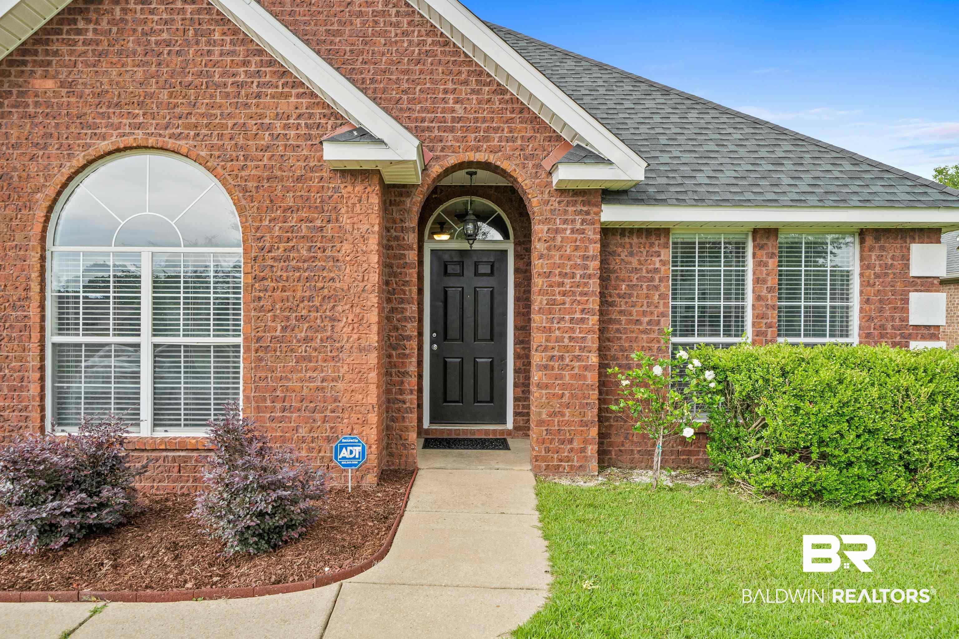 9552 Collier Loop Daphne, AL 36526 - Photo 3 of 28 Doorway to property featuring brick siding, a shingled roof, and a yard