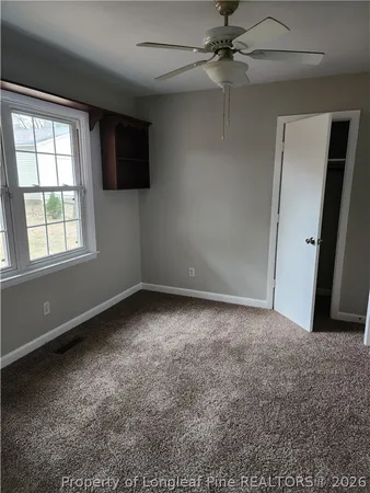 an empty room with a window and a fan