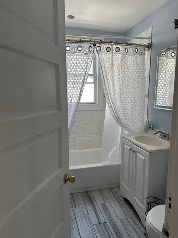 a bathroom with a granite countertop bathtub shower sink vanity and toilet