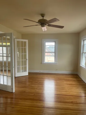 a view of an empty room with wooden floor and a window
