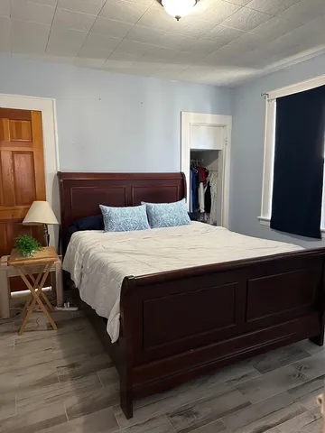 a large bedroom with wooden floor and bed