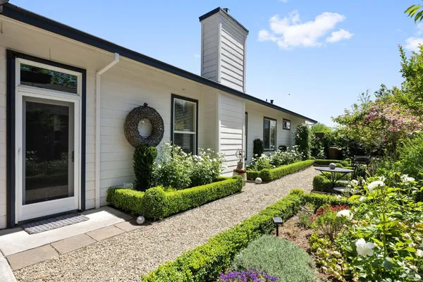 a view of a patio with table and chairs potted plants and floor to ceiling window