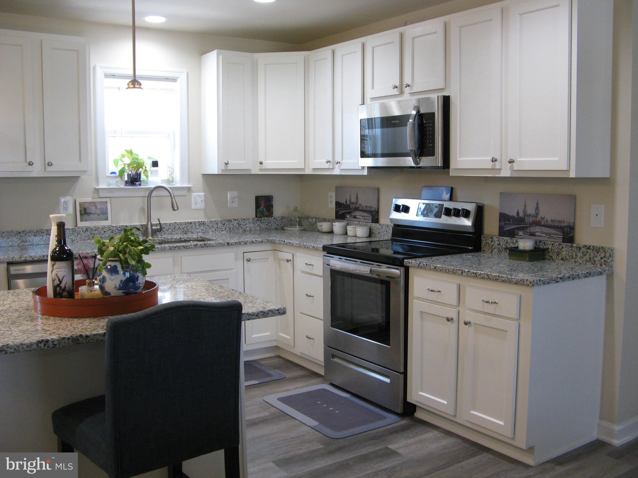 57 Oak Lane Colonial Beach, VA 22443 - Photo 13 of 47 a kitchen with stainless steel appliances granite countertop a stove a sink dishwasher and white cabinets with wooden floor