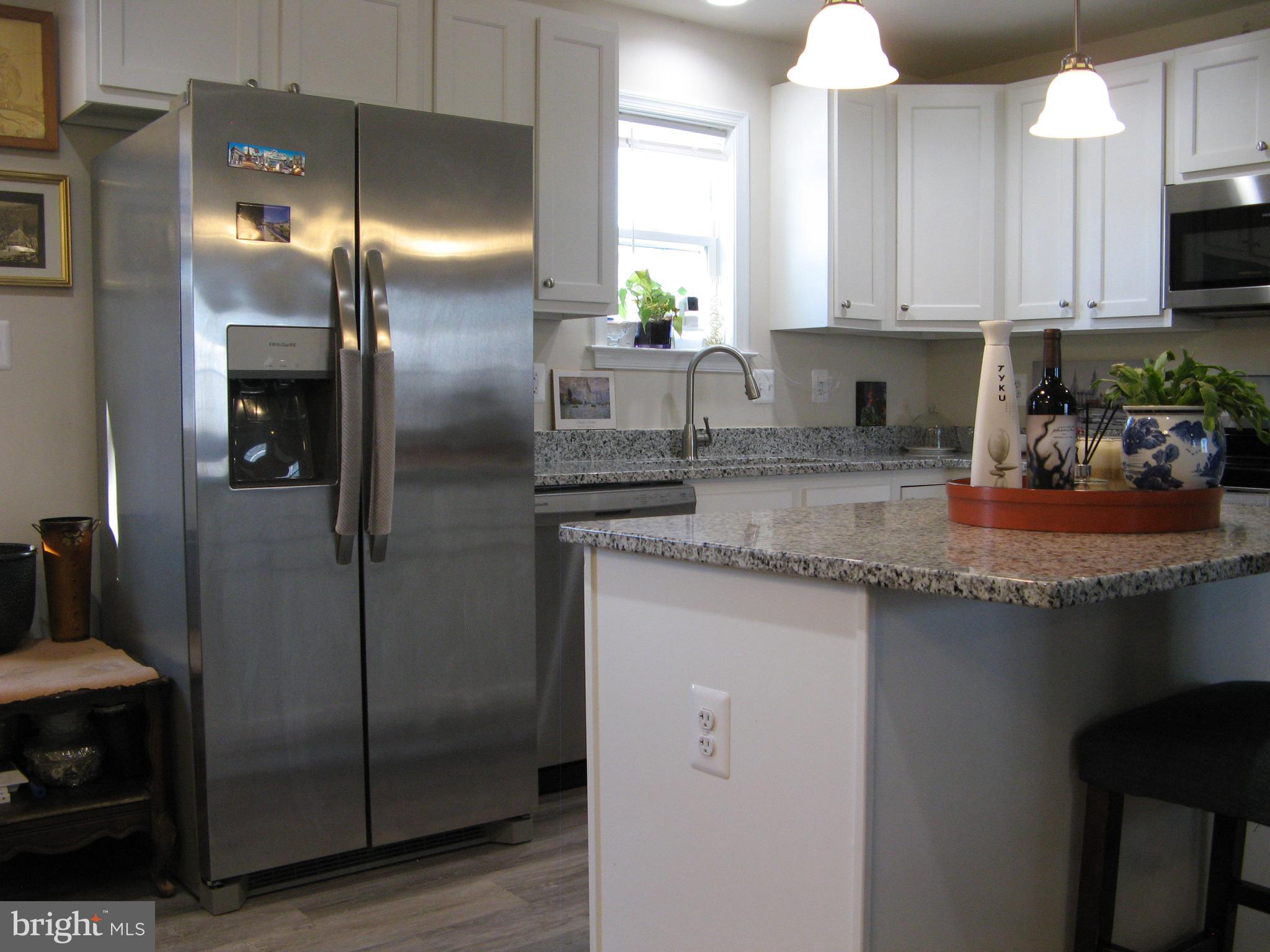 57 Oak Lane Colonial Beach, VA 22443 - Photo 19 of 47 a kitchen with stainless steel appliances granite countertop a refrigerator a sink a stove a washer dryer and a dining table