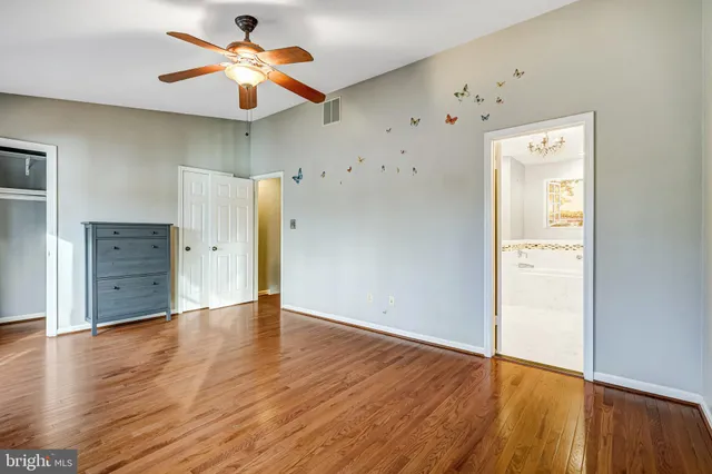 an empty room with wooden floor and a ceiling fan