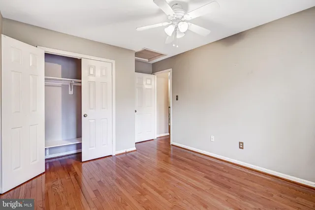 an empty room with wooden floor closet and windows