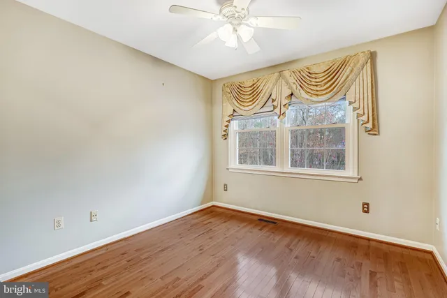 an empty room with a window and ceiling fan