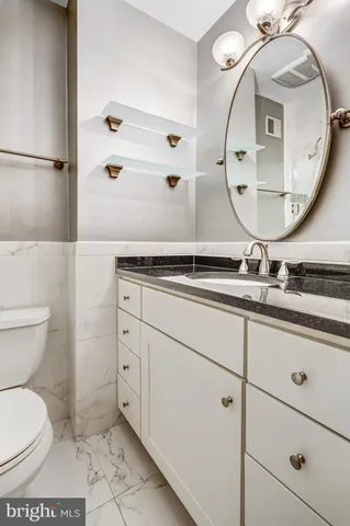 a bathroom with a granite countertop toilet sink and mirror