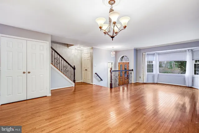 a view of an empty room with wooden floor and windows
