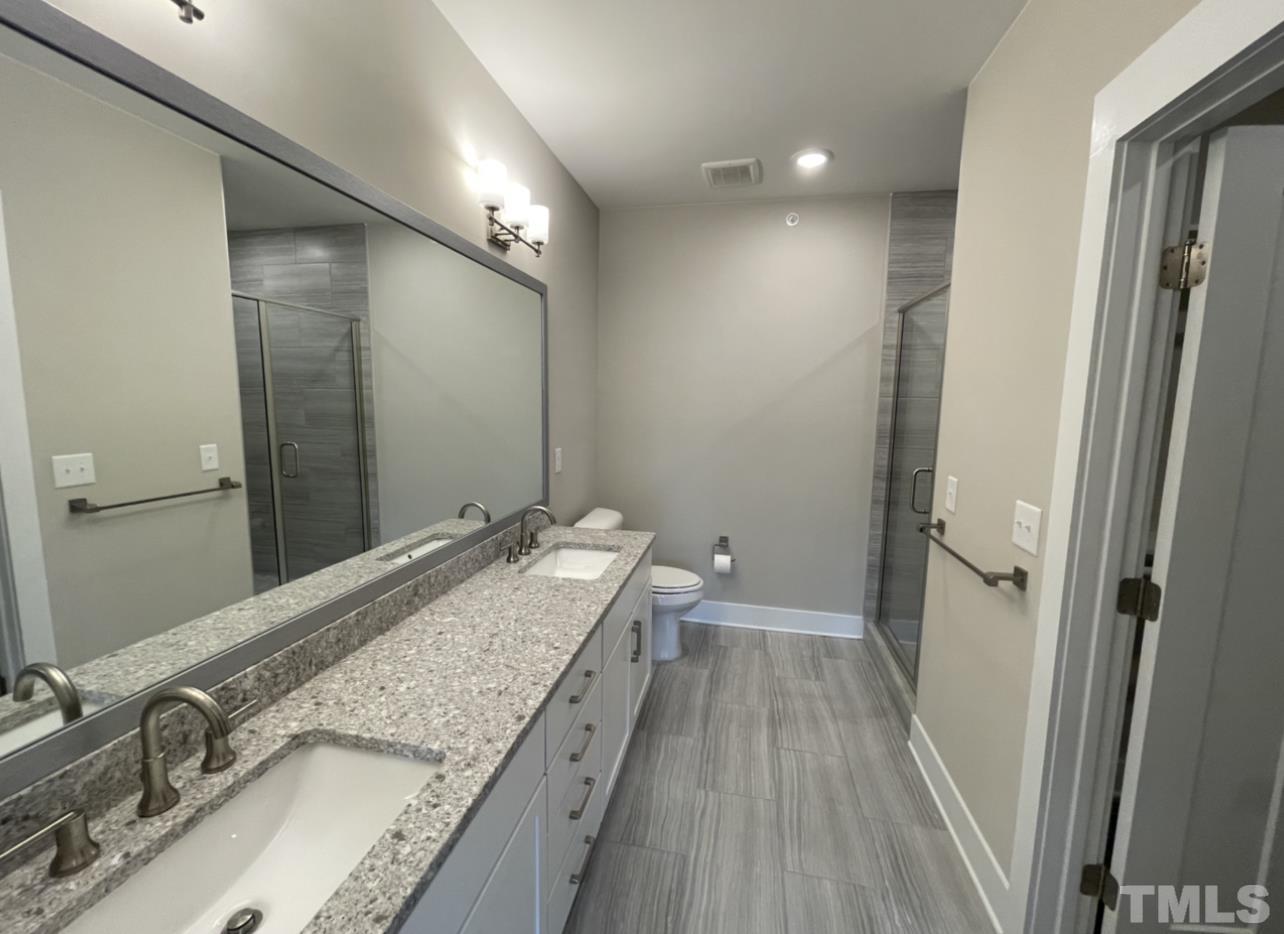 105 Chatham Walk Lane, Unit 404 Cary, NC 27511 - Photo 13 of 33 a bathroom with a granite countertop sink a mirror and a toilet