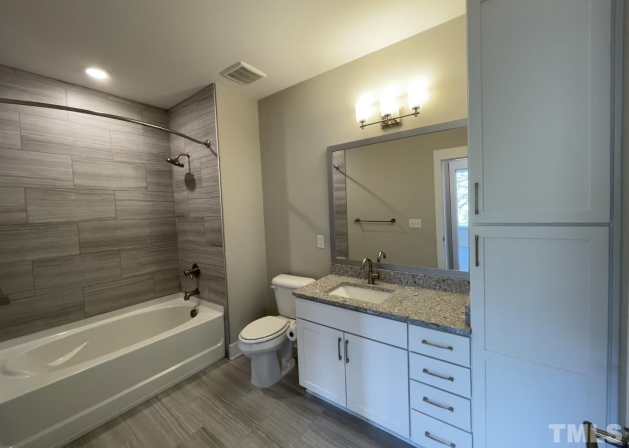 105 Chatham Walk Lane, Unit 404 Cary, NC 27511 - Photo 21 of 33 a bathroom with a granite countertop tub sink toilet and mirror