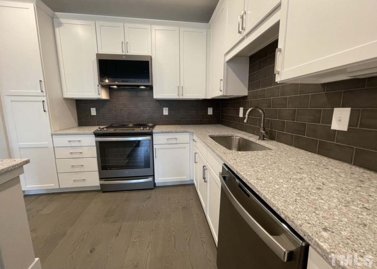 105 Chatham Walk Lane, Unit 404 Cary, NC 27511 - Photo 23 of 33 a kitchen with stainless steel appliances granite countertop a sink stove and microwave