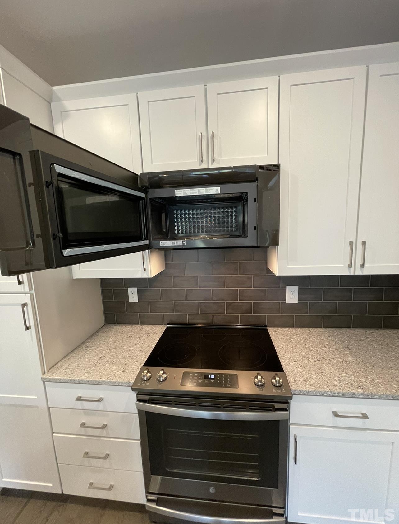 105 Chatham Walk Lane, Unit 404 Cary, NC 27511 - Photo 25 of 33 a kitchen with granite countertop a stove and a microwave