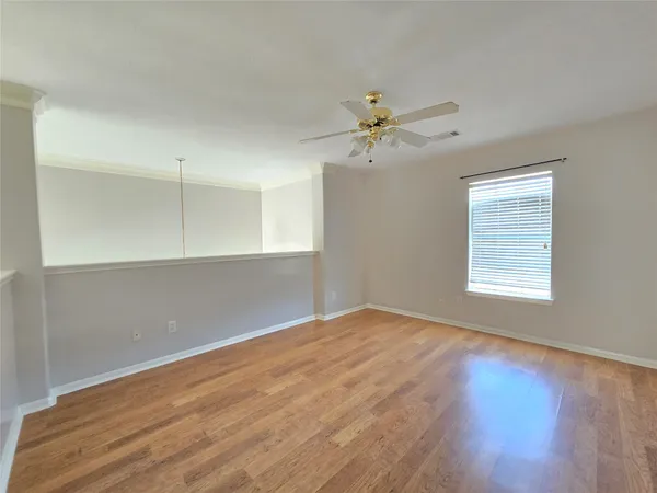a view of empty room with wooden floor and fan