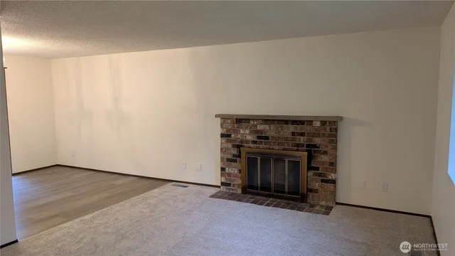 a view of an empty room with wooden floor and a fireplace