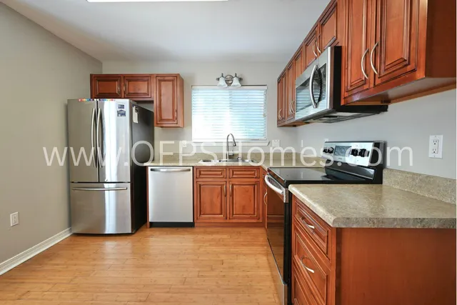 a kitchen with stainless steel appliances granite countertop a refrigerator a sink dishwasher a stove with wooden cabinets and floor