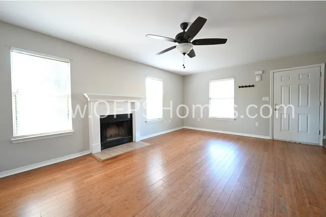 an empty room with wooden floor fireplace and windows