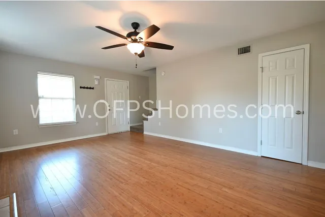 a view of an empty room with a window and wooden floor