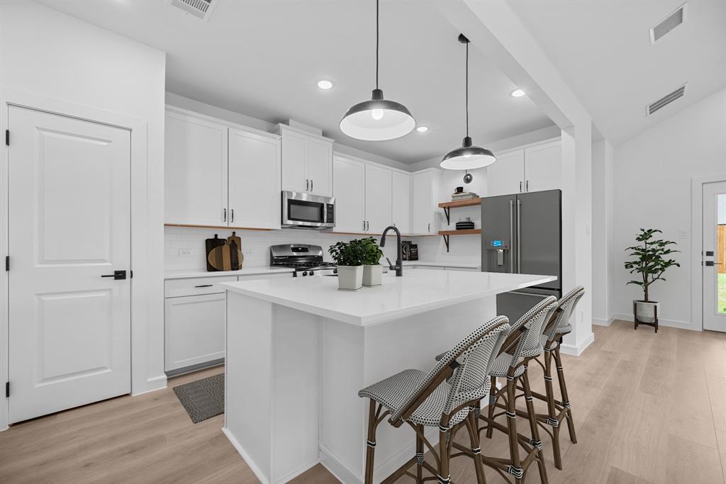 2209 Maple Ridge Drive Van Alstyne, TX 75495 - Photo 10 of 22 a kitchen with stainless steel appliances a table chairs refrigerator and microwave