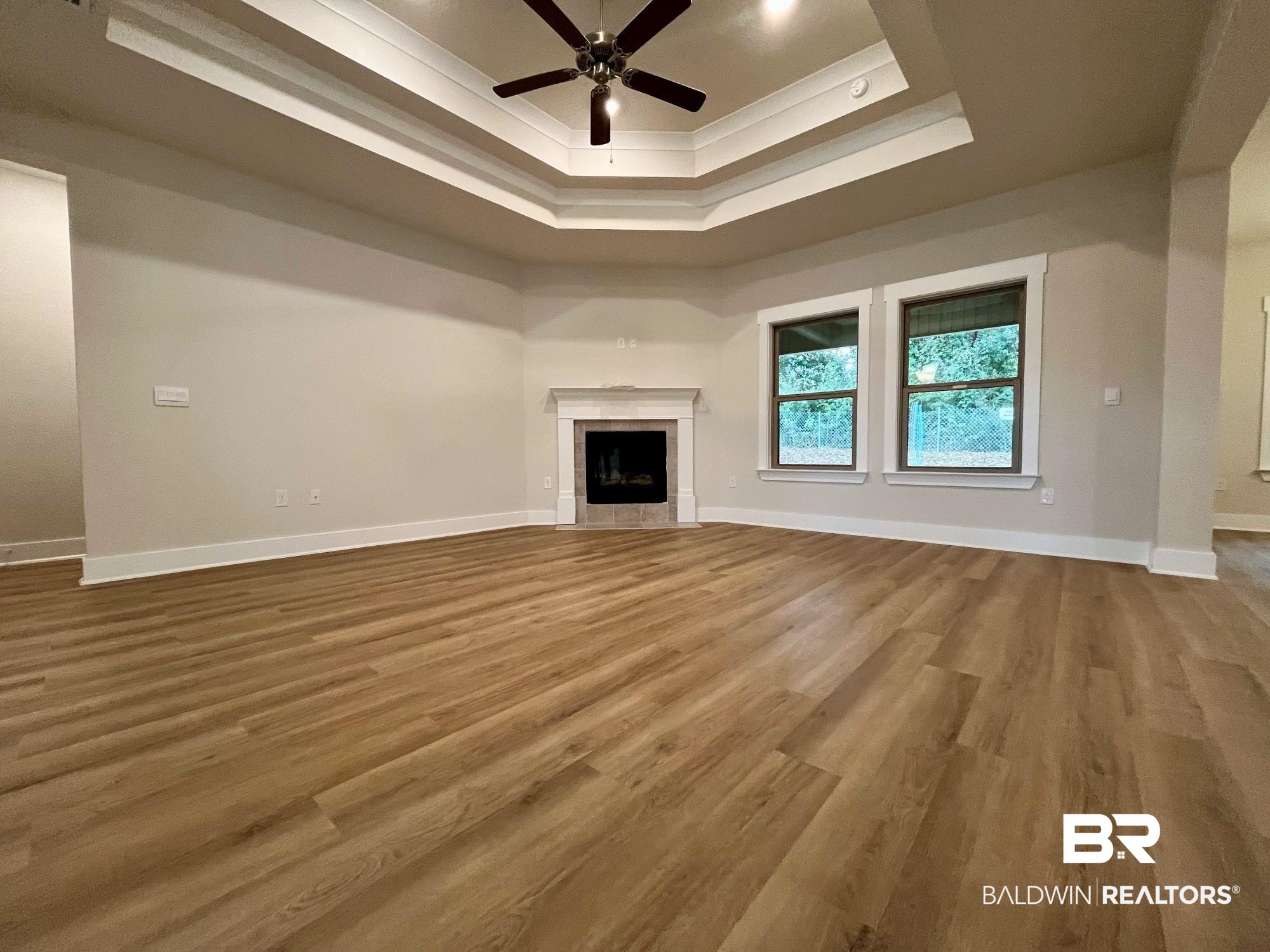 330 Barndling Street Fairhope, AL 36532 - Photo 9 of 31 Unfurnished living room with ceiling fan, hardwood / wood-style flooring, a tiled fireplace, and a raised ceiling