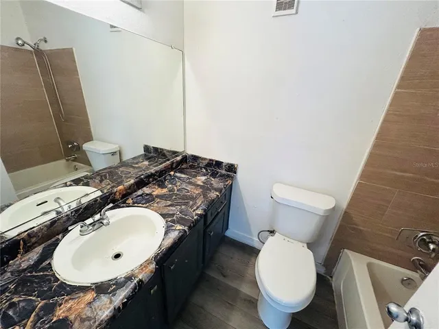 a bathroom with a granite countertop toilet sink and mirror