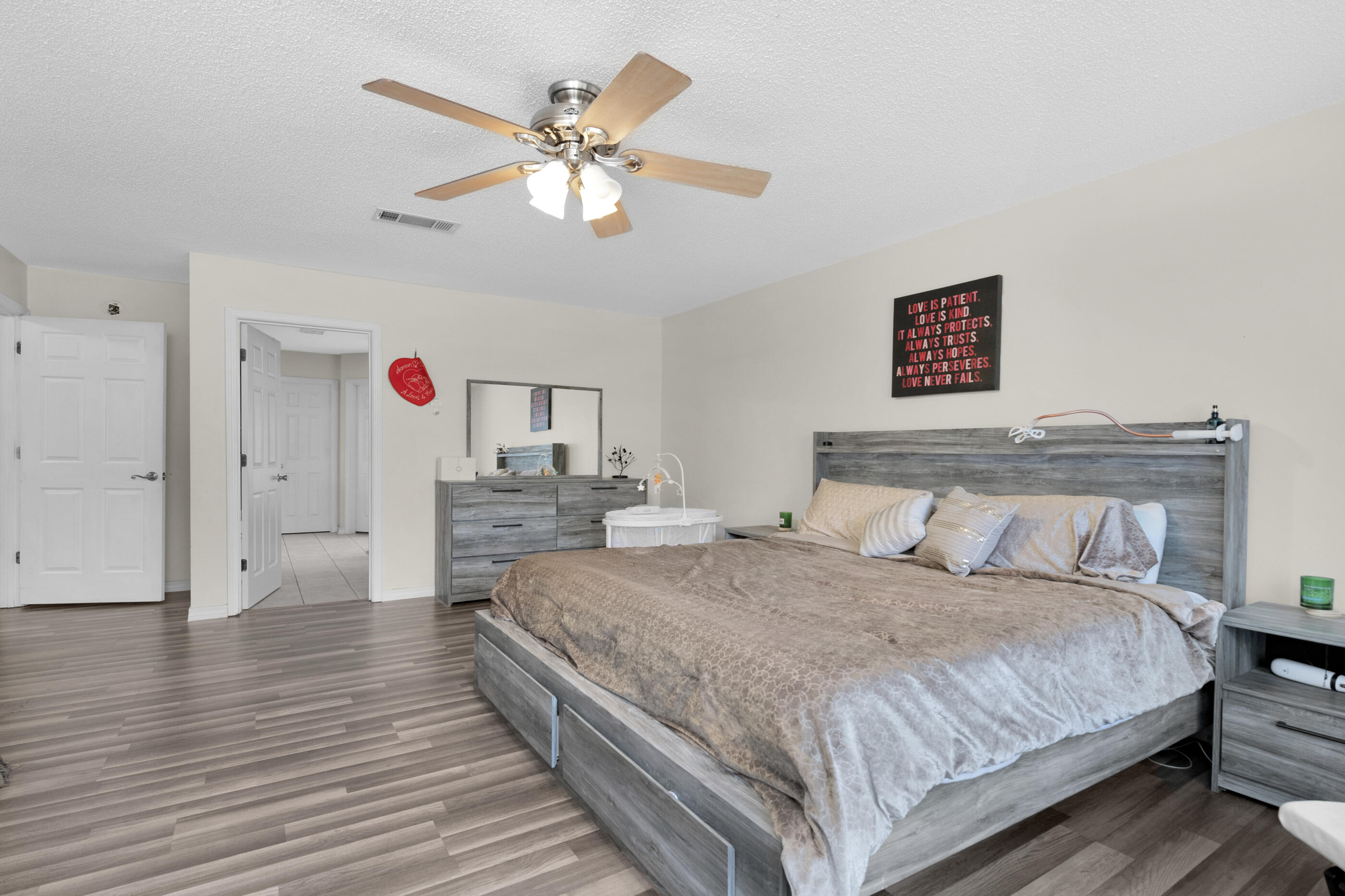 6215 Shire Lane Crestview, FL 32536 - Photo 24 of 36 a spacious bedroom with a bed and a chandelier