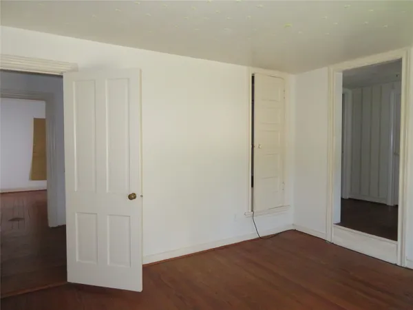 an empty room with wooden floor and closet area