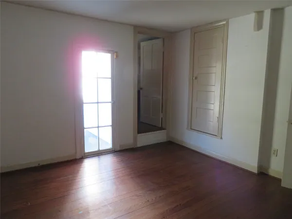 an empty room with wooden floor and windows with curtains
