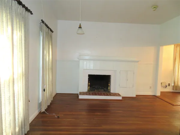 a view of empty room with wooden floor and fireplace