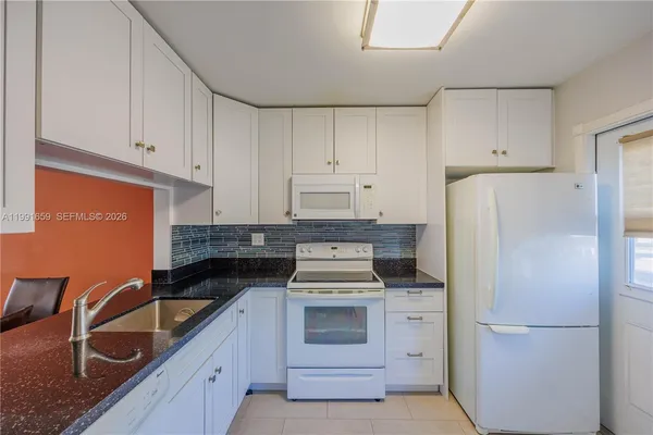 a kitchen with white cabinets and white appliances