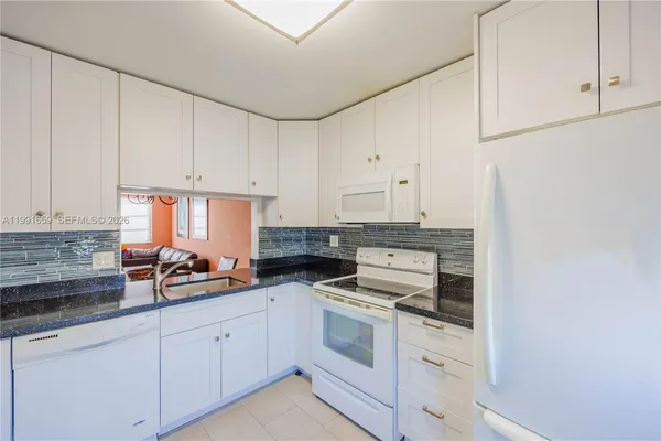 a kitchen with white cabinets and white appliances