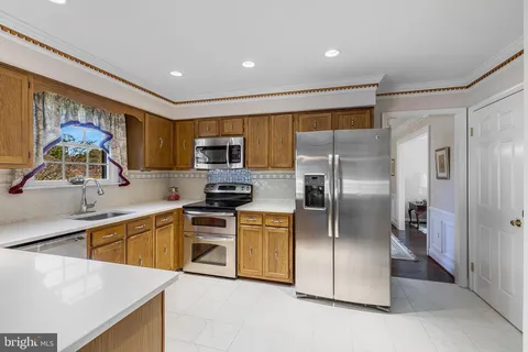 a kitchen with stainless steel appliances granite countertop a refrigerator a sink a stove top oven and a refrigerator