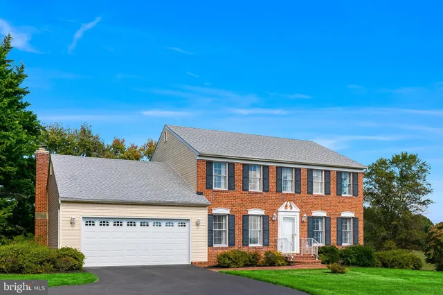 a view of a big yard in front of a brick house with large windows
