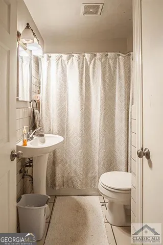a bathroom with a sink a toilet a mirror and shower curtain