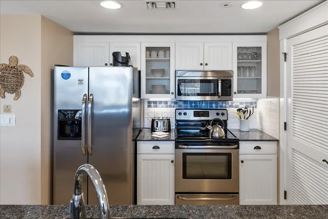 a kitchen with stainless steel appliances kitchen island granite countertop a table chairs refrigerator and microwave