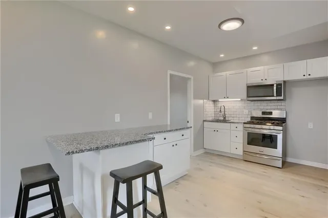 a kitchen with granite countertop white cabinets and white appliances