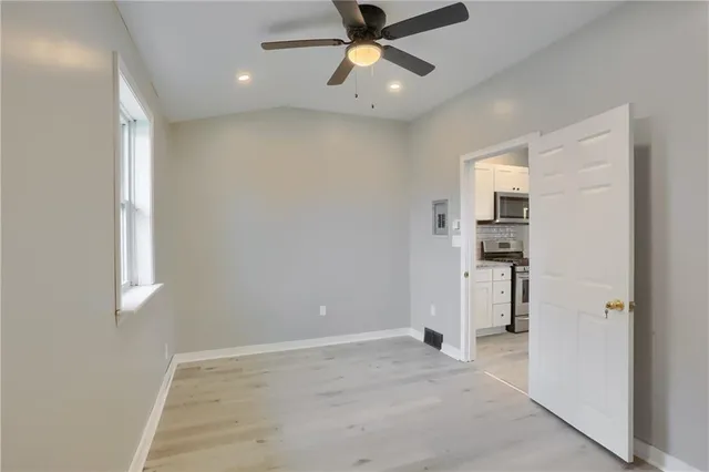 a view of empty room with wooden floor and fan