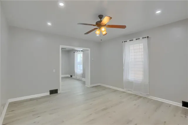 an empty room with windows and fan