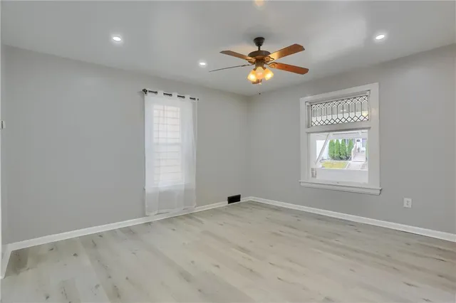 an empty room with windows and fan