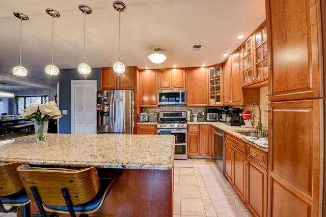 a kitchen with stainless steel appliances kitchen island granite countertop a stove a sink and a refrigerator