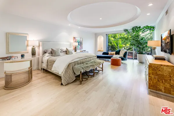 a spacious bedroom with a bed a couch and a potted plant