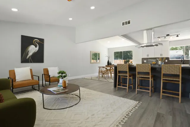 a living room with furniture kitchen view and a wooden floor