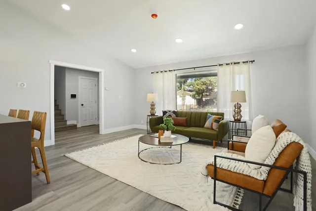 a living room with furniture a flat screen tv and kitchen view