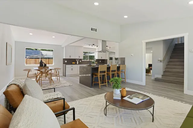 a kitchen with stainless steel appliances kitchen island granite countertop a sink a stove a dining table and chairs with wooden floor